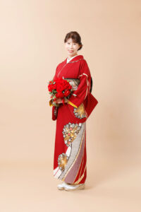 赤のお着物と赤バラブーケを持って還暦祝いの記念写真